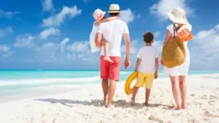 4 osobowa rodzina spaceruje po plaży podczas urlopu wypoczynkowego